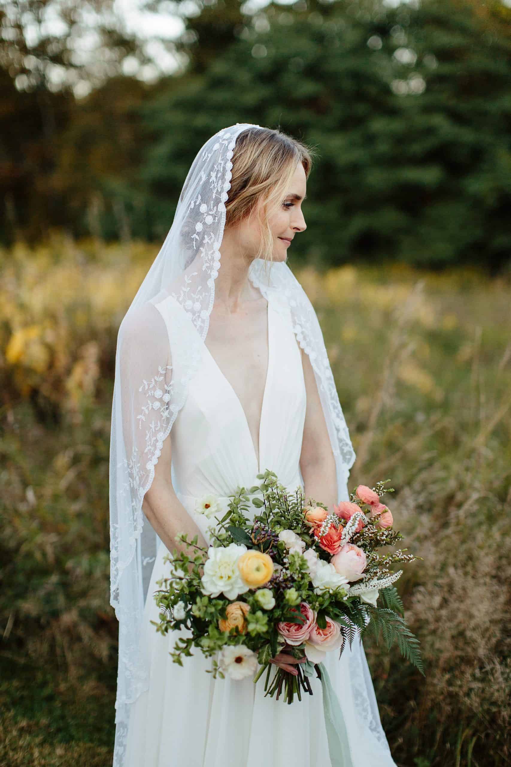 Bride holding bouquet from Olive & June floral farm at her M&D farm wedding in the Catskills capture by upstate new york wedding photographers The Light and Color