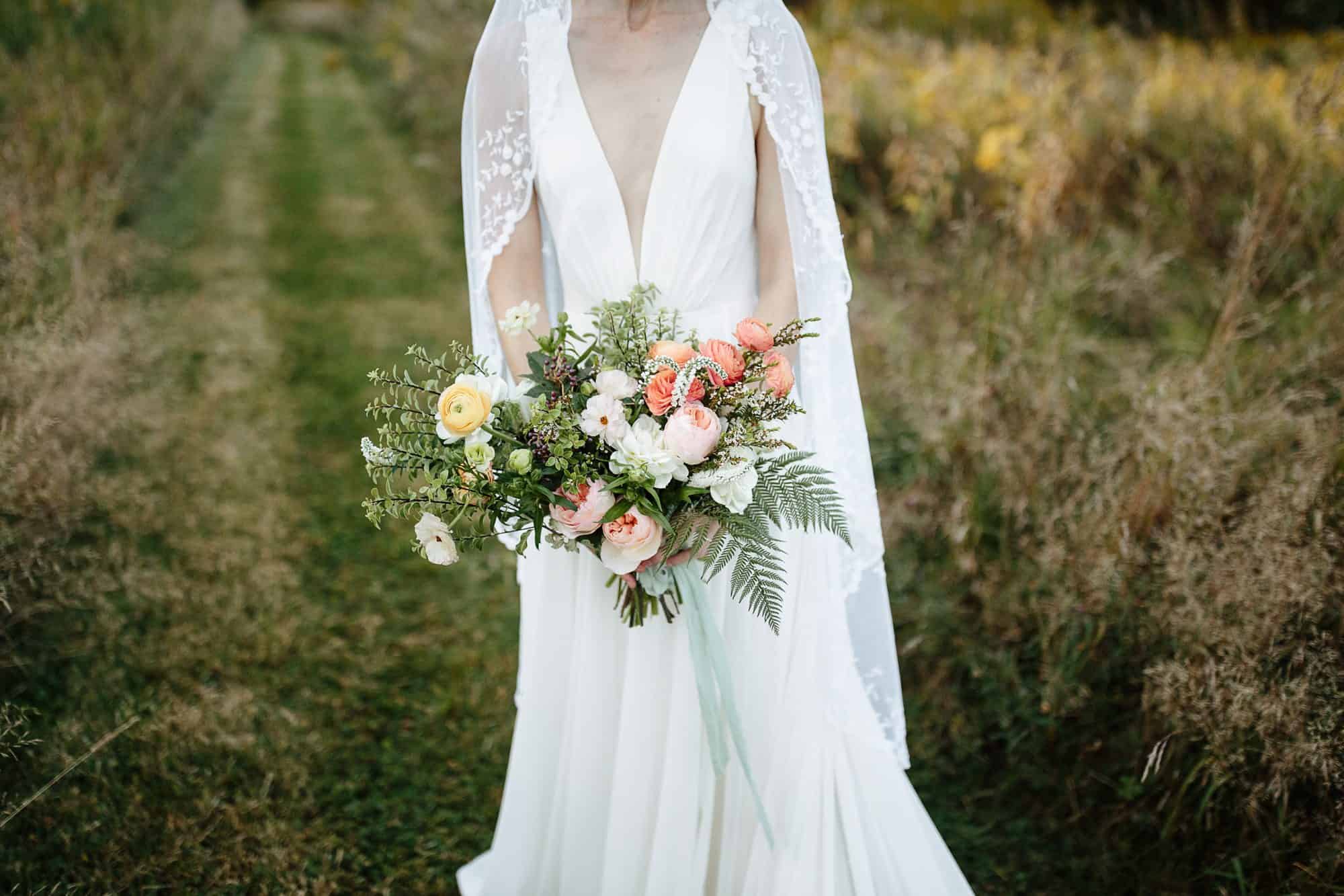 Bride holding bouquet from Olive & June floral farm at her M&D farm wedding in the Catskills capture by upstate new york wedding photographers The Light and Color