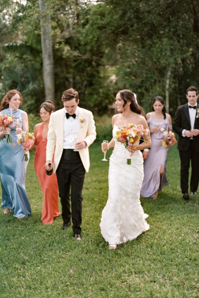 Couple walking across grass with wedding party at Deering Estate Wedding